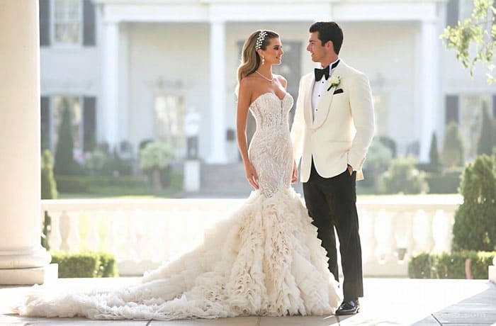 Fashion illustration of Jennifer Lopez in a custom Ralph Lauren ruffled wedding gown standing next to Ben Affleck in a white tuxedo