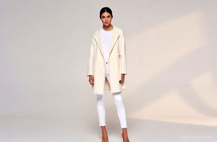 Fashion sketch of Meghan Markle wearing a camel coat over a white button-down and white jeans, accessorized with tan pumps